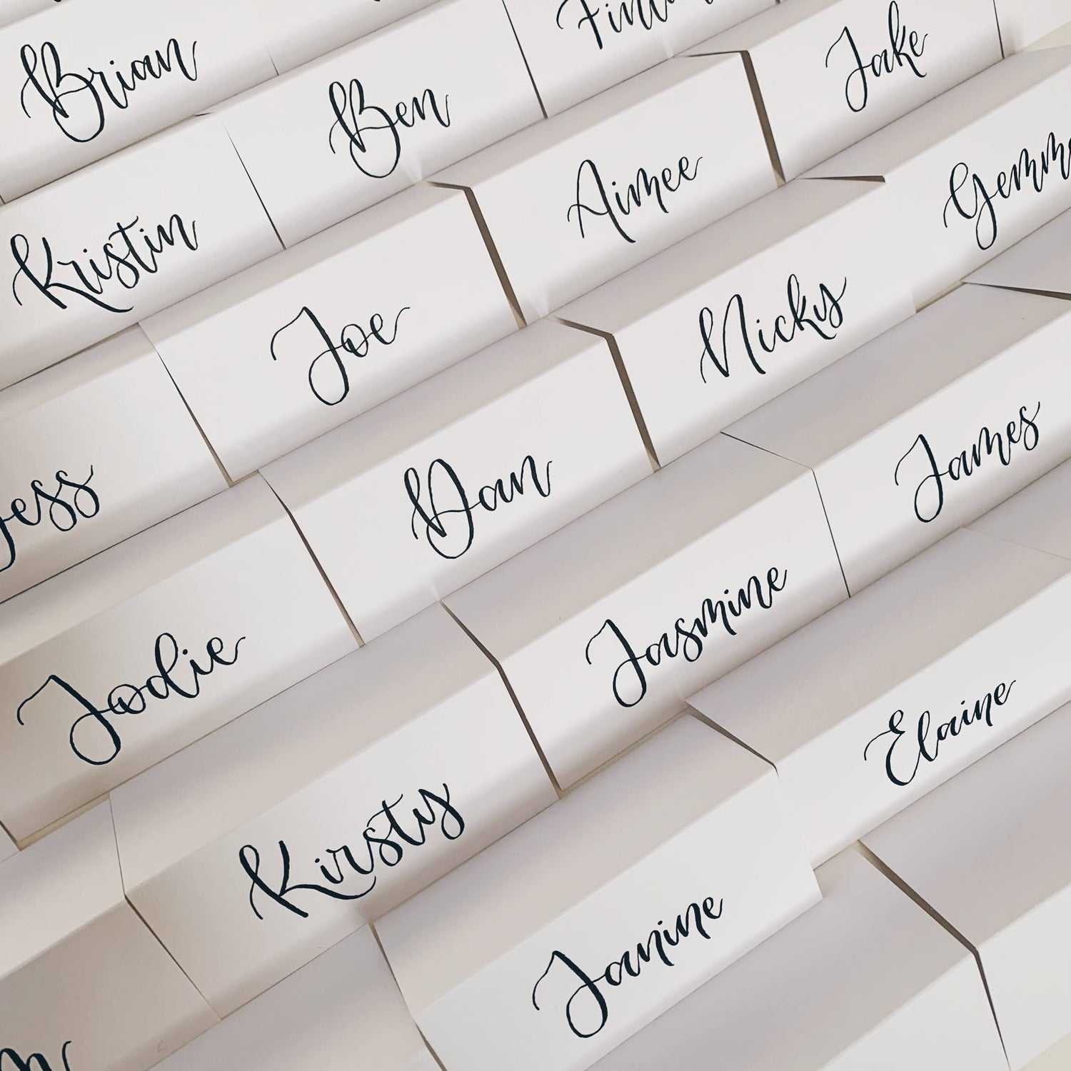 White paper place cards with black calligraphy names for Kent wedding