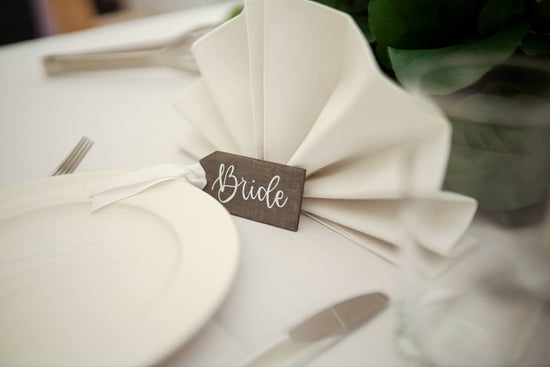wedding place card names on a wooden grey tag with white calligraphy lettering