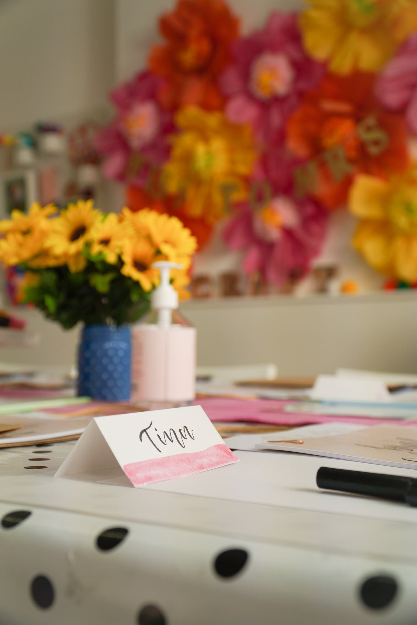 white place card with soft pink watercolour painting to the bottom and black brush calligraphy names