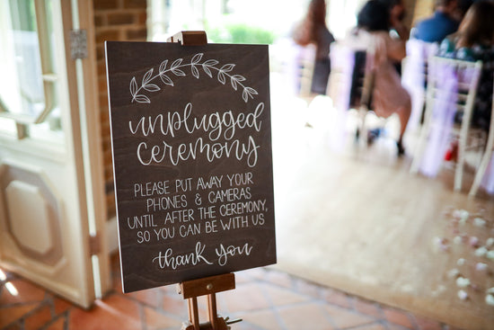 Wooden A3 grey wedding sign standing on easel at Essex wedding venue, asking for an unplugged wedding ceremony