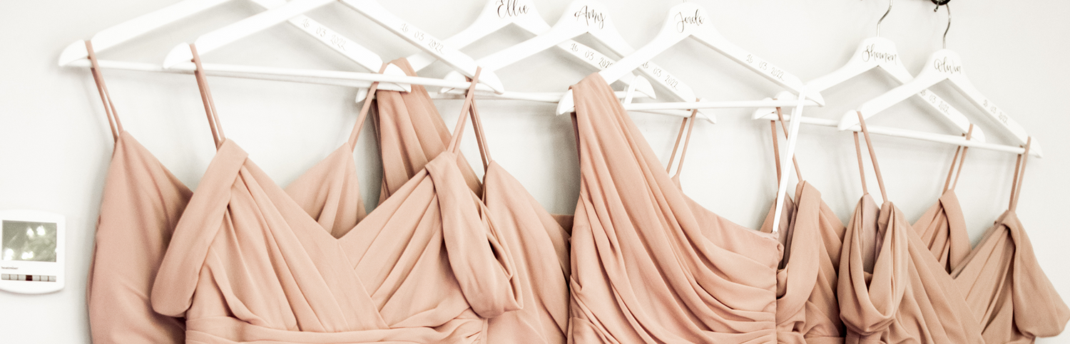 Brush bridesmaid dresses hanging on white personalised wedding hangers, with names and wedding date