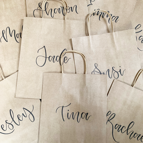 Personalised kraft paper bags, hand lettered with names in black brush pen
