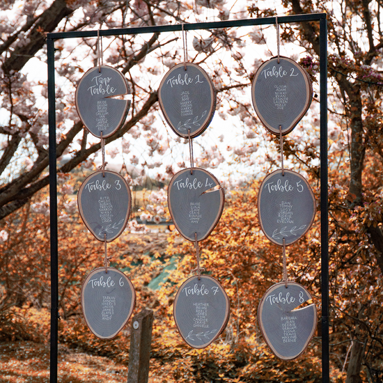 Hanging table plan made from wooden slices, painted in grey with white lettering